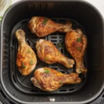 Crispy and juicy Air Fryer Chicken Legs served on a plate with herbs.